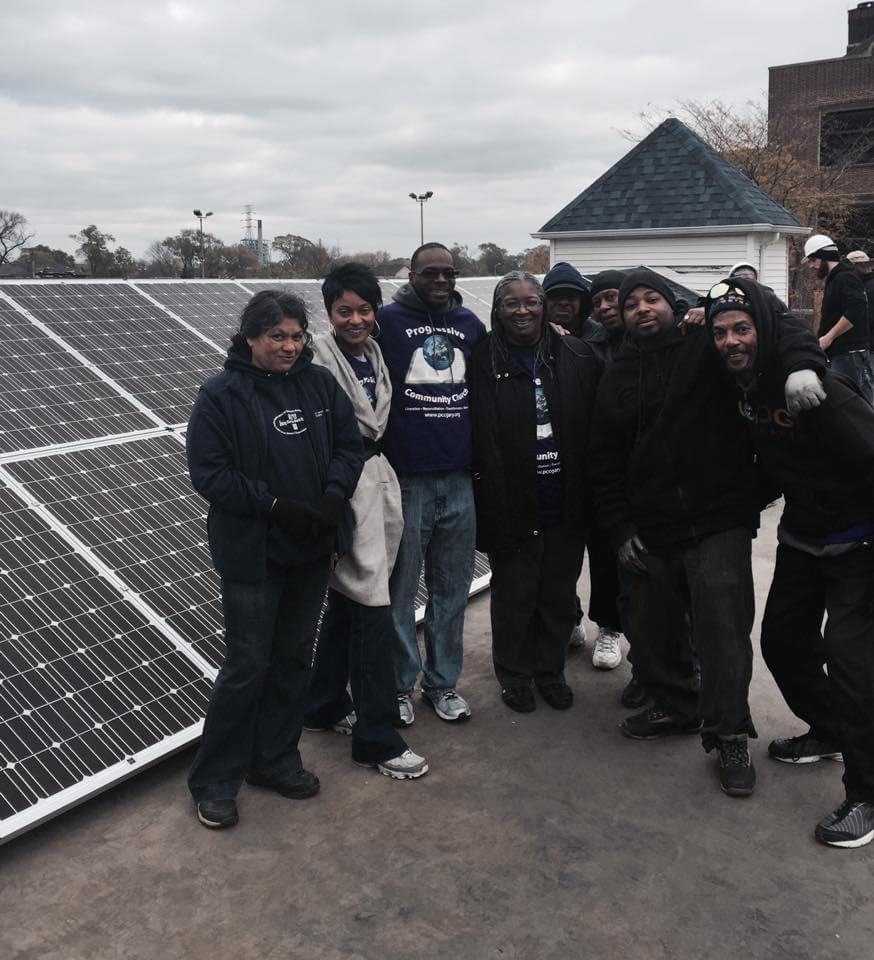 Pastor Whittaker and community members pose for a photo in front of the Progressive Community Church solar panels